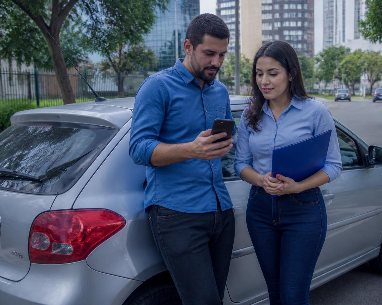 Comprador e vendedor conferindo informações de um carro usado pelo celular